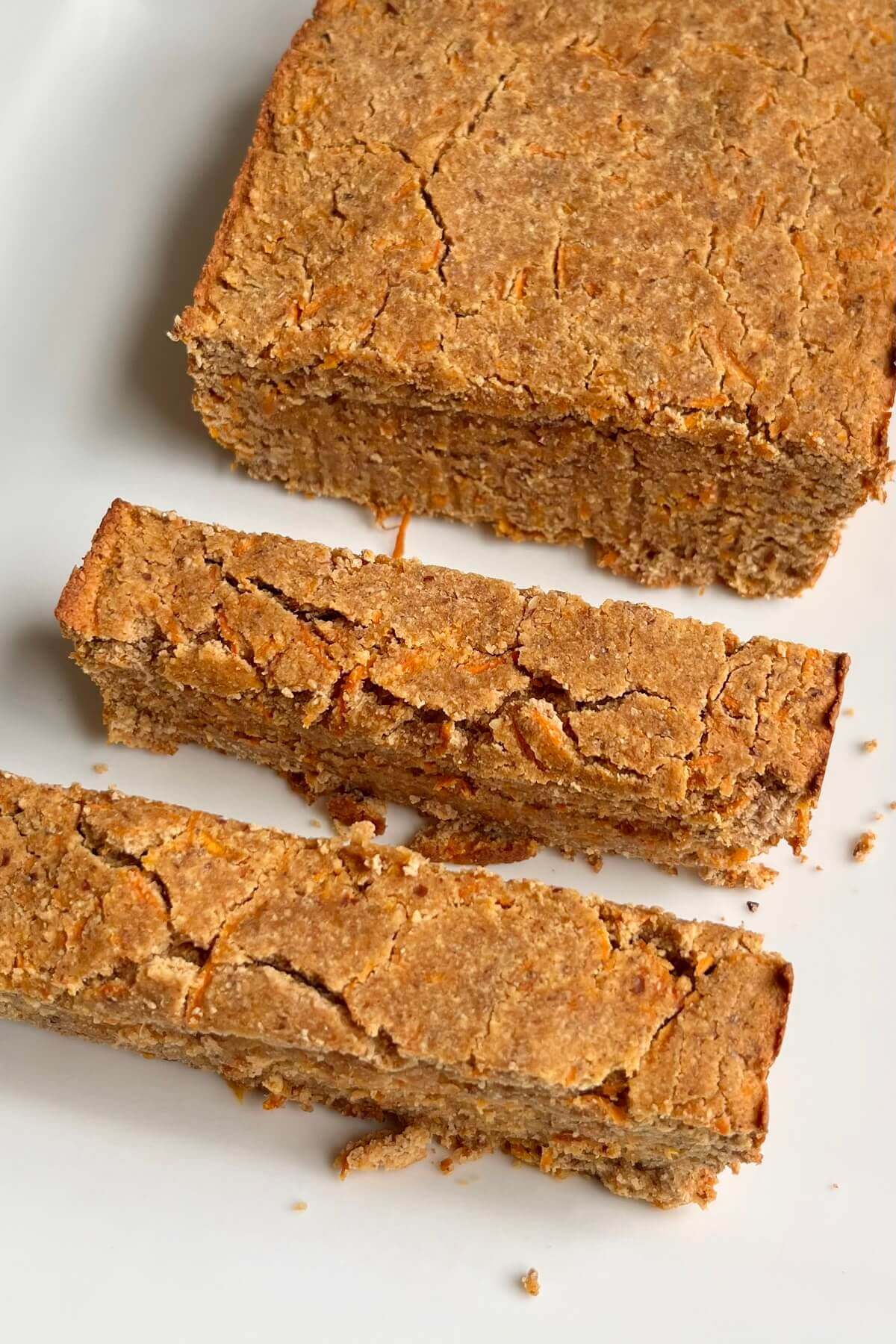 A loaf of vegan carrot cake with two slices cut.