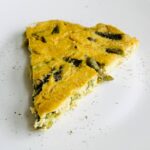 A slice of vegan asparagus frittata on a white plate.