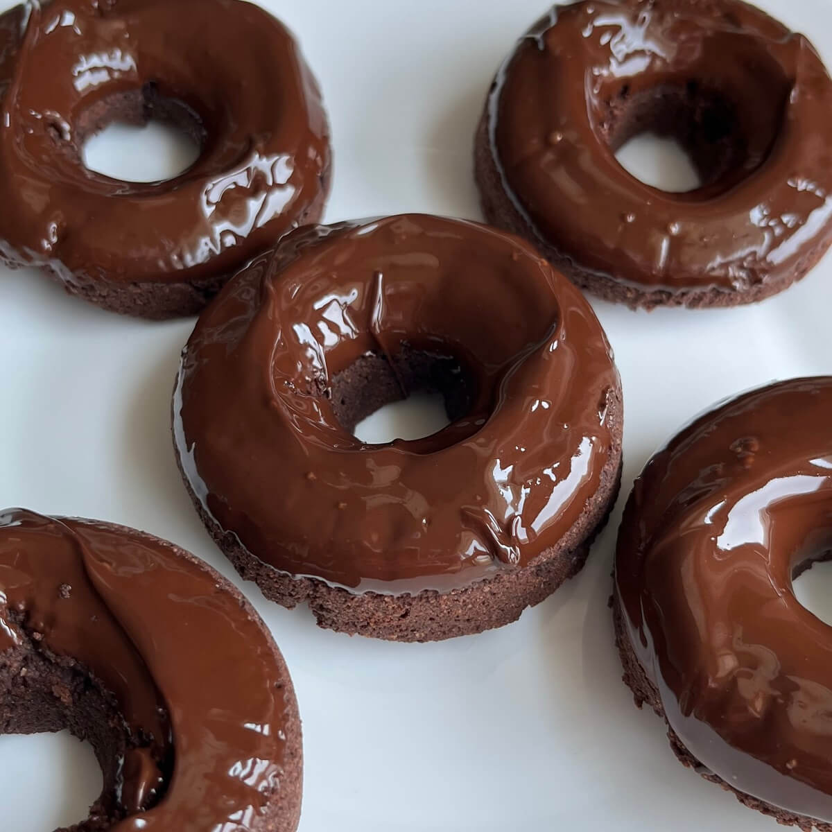 Vegan glazed donuts on a white plate.
