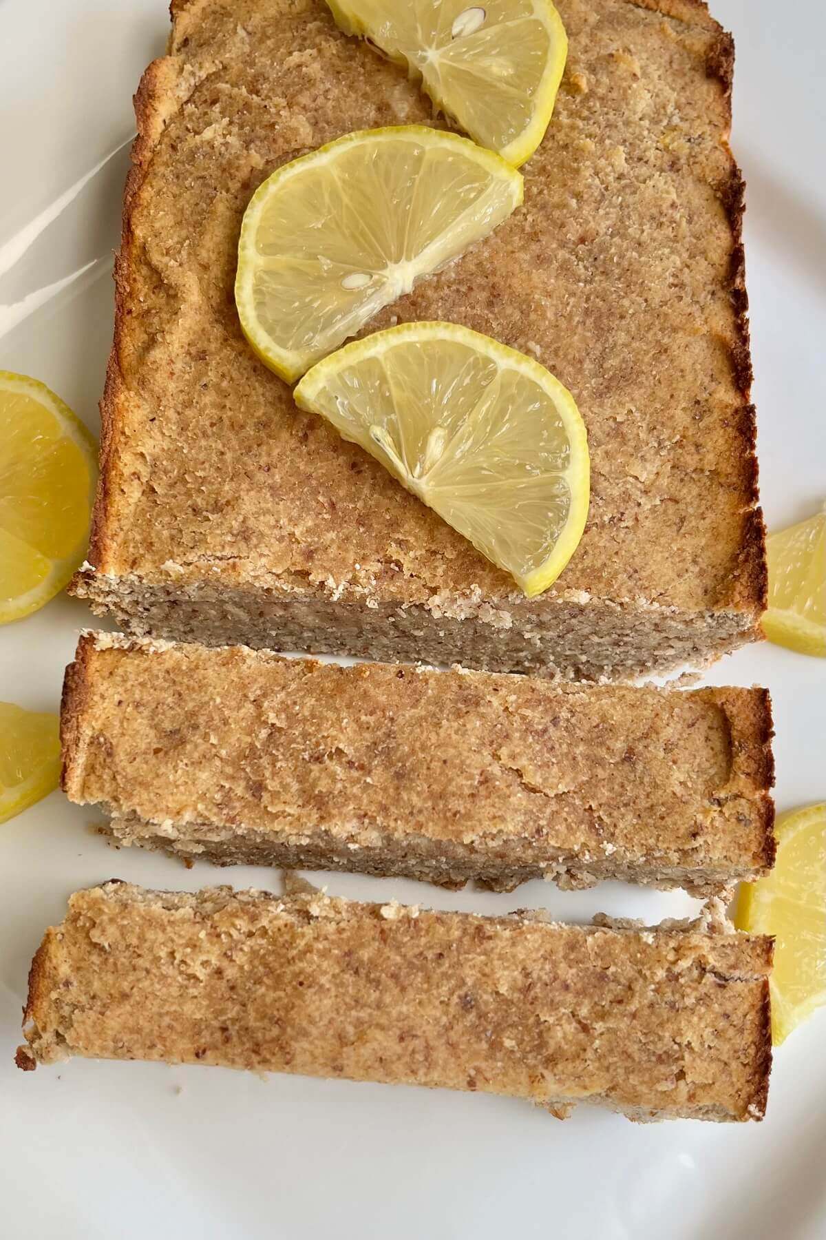 A vegan lemon loaf garnished with lemon slices.