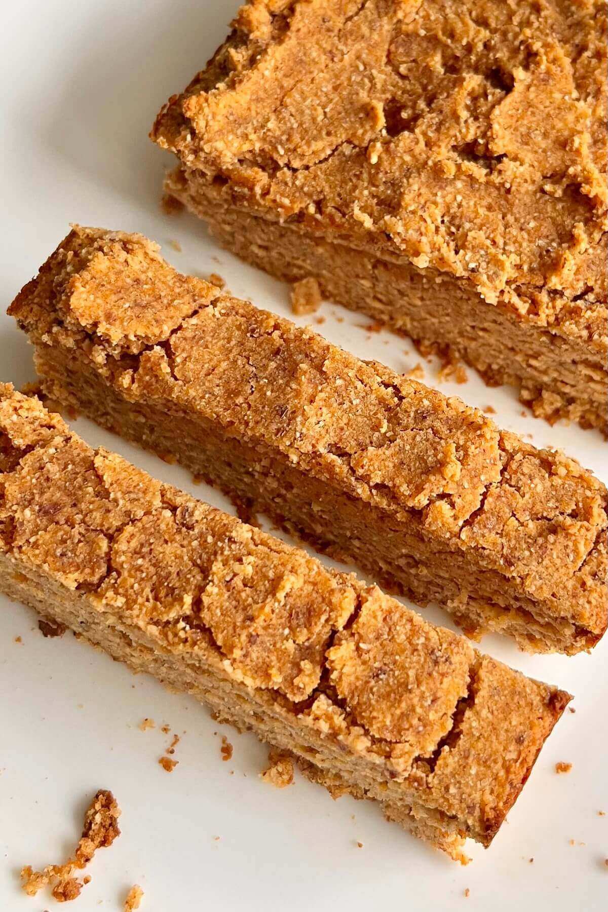 A loaf of vegan sweet potato bread with two slices cut on a white plate.