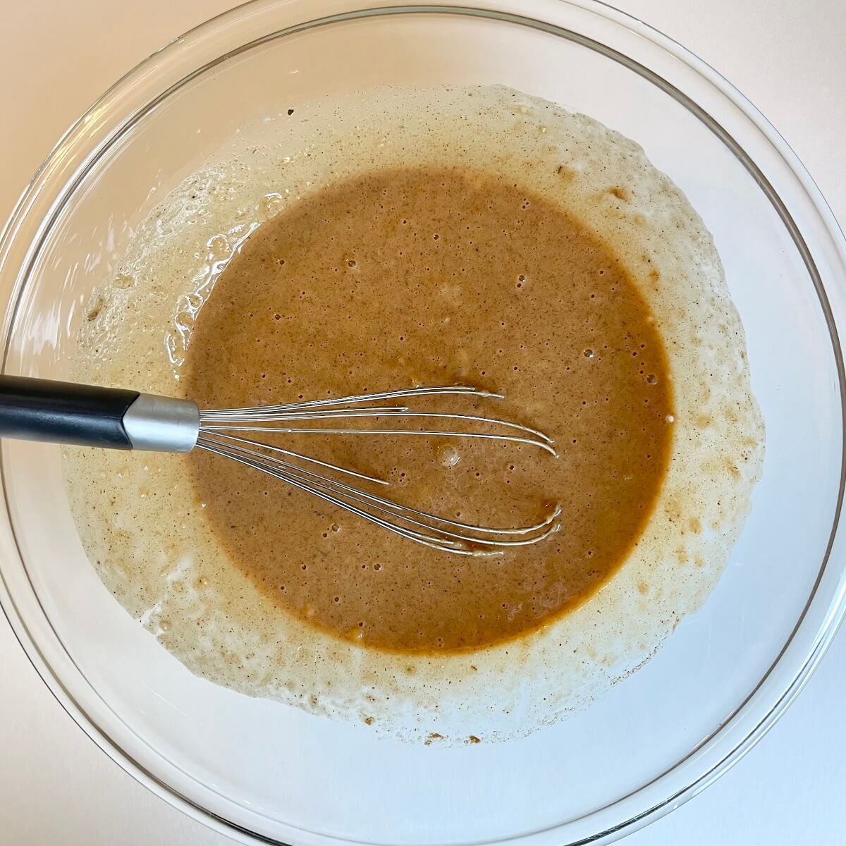 Wet ingredients for vegan muffins in a glass mixing bowl.