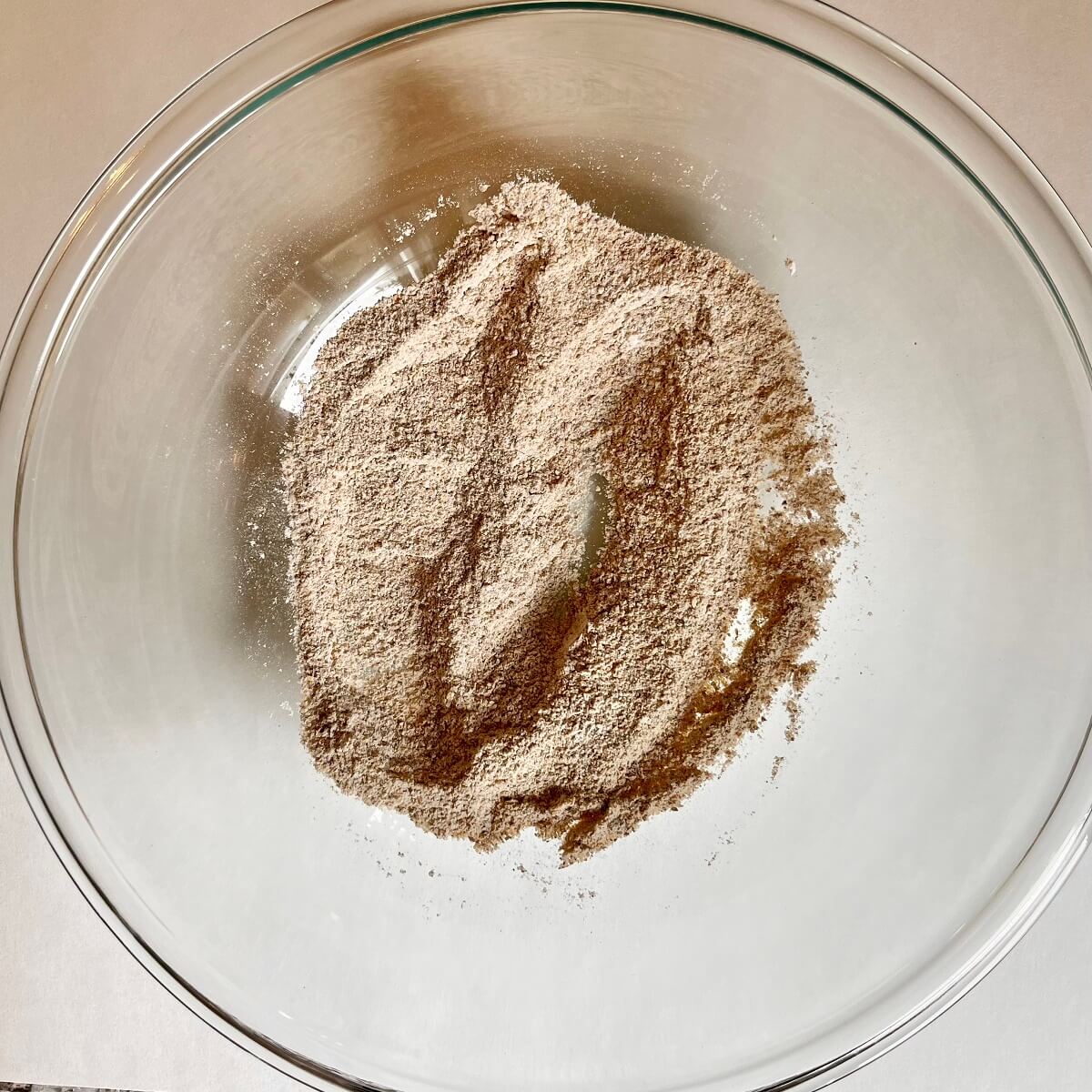 Dry ingredients for crackers in a glass mixing bowl.