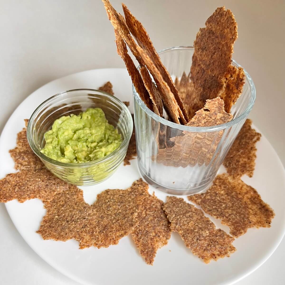 Flaxseed crackers next to a dish of guacamole.