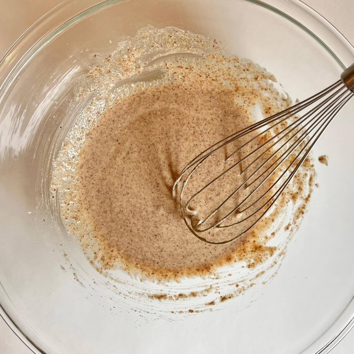 Raw cracker batter being mixed with a whisk in a glass mixing bowl.