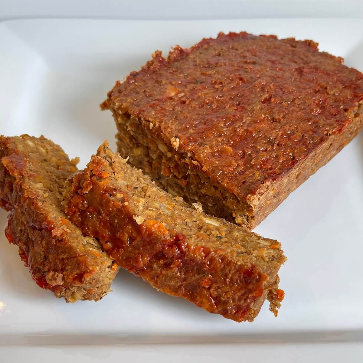 Vegan meatloaf with two thick slices cut on a white platter.