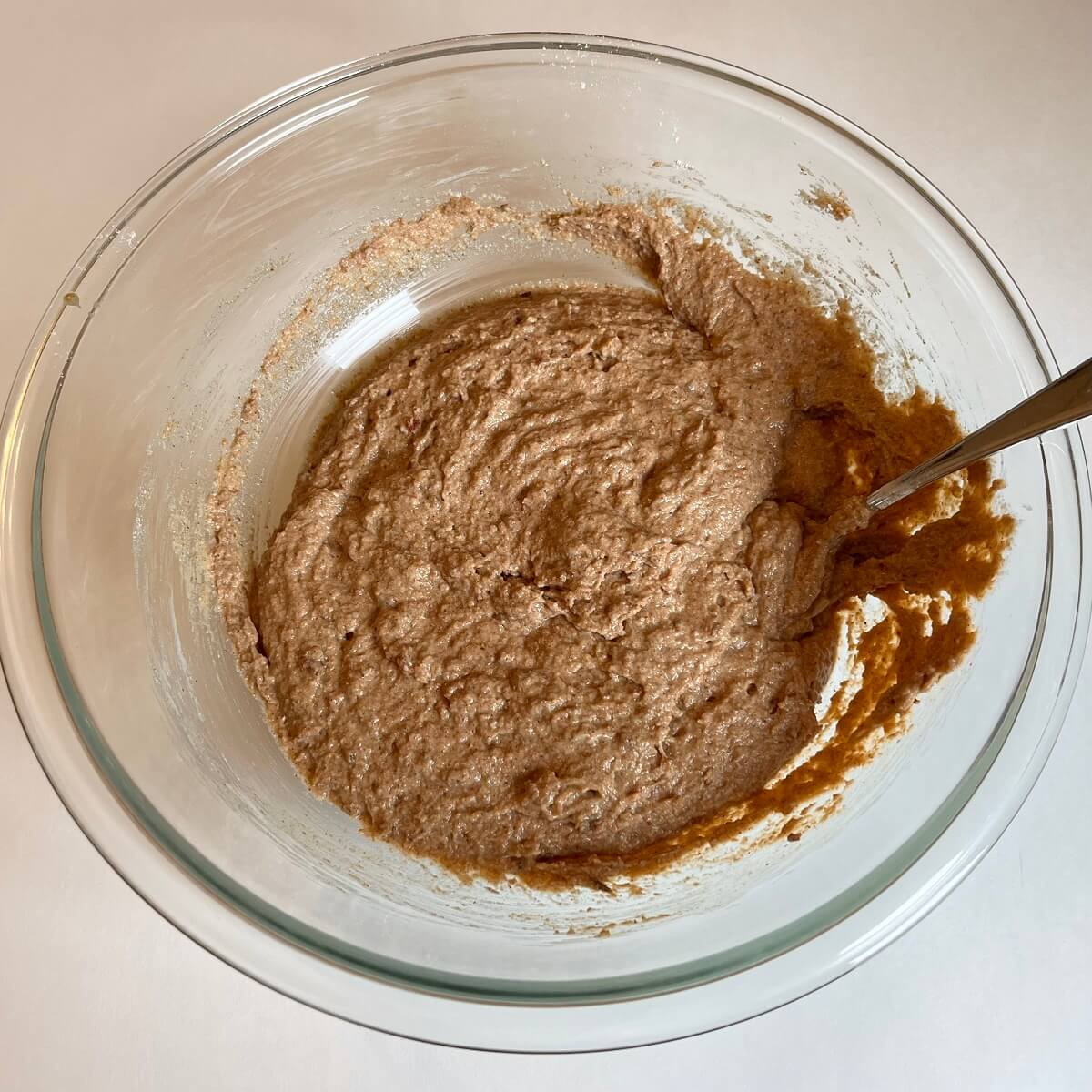 Light brown muffin batter in a glass bowl.