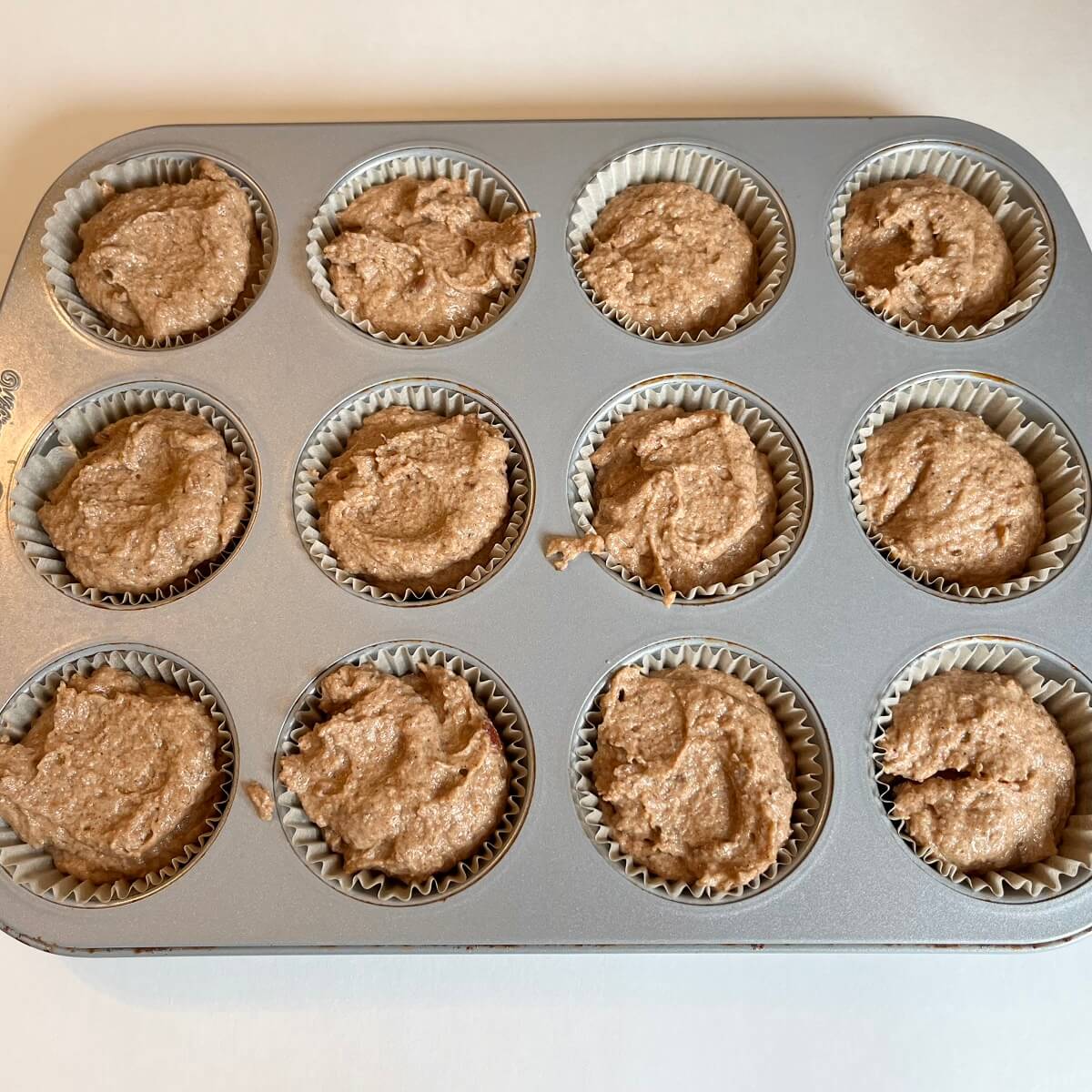 Raw muffins sweetened with dates in a metal pan.