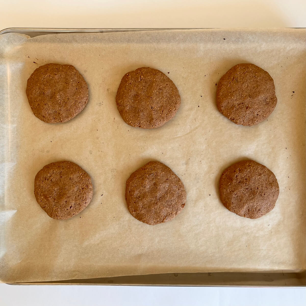 Baked cookies made with figs on a sheet pan lined with parchment paper.