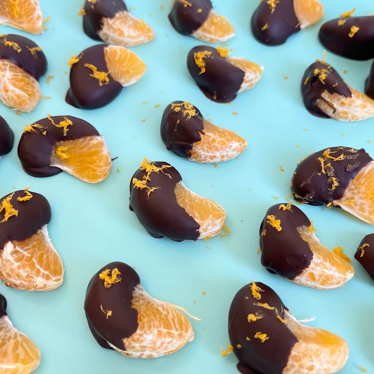 Chilled chocolate dipped clementine segments on a silicone baking mat.