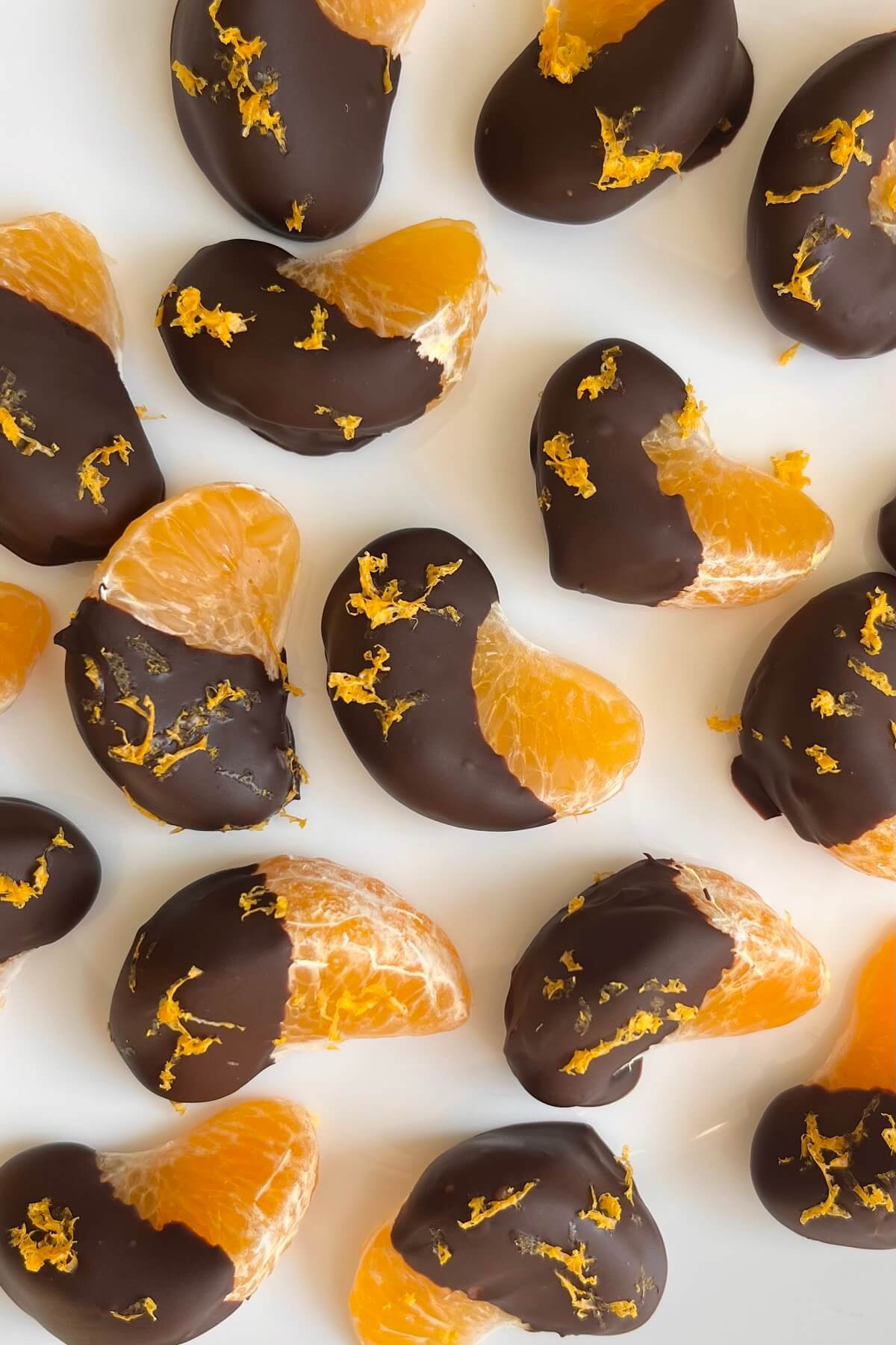 Chocolate covered clementine orange segments on a white plate.