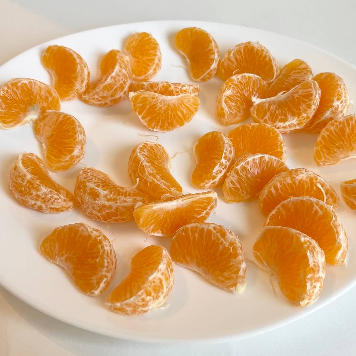 Clementine orange segments on a white plate.