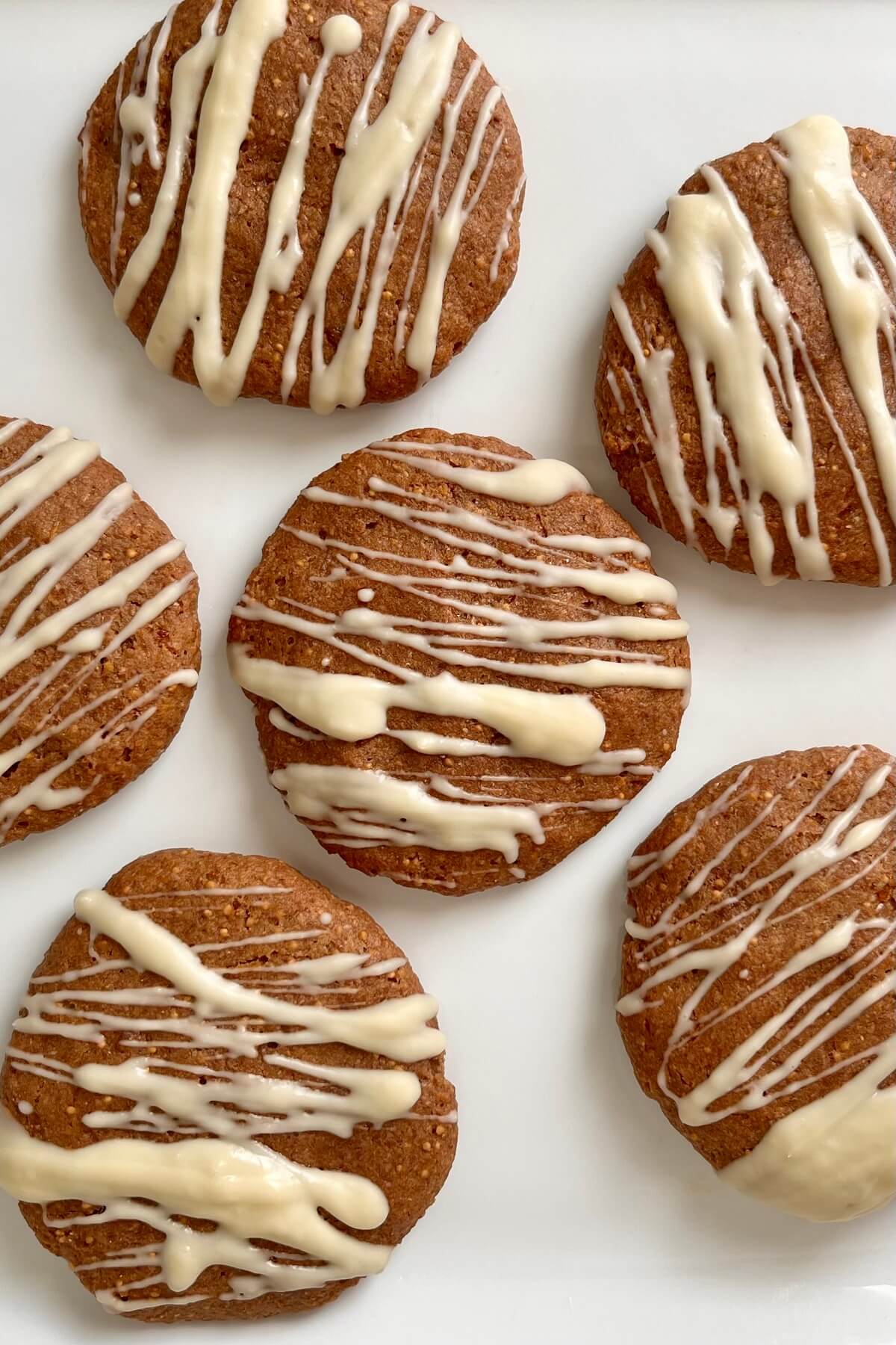 White chocolate drizzled cookies made with figs on a white plate.
