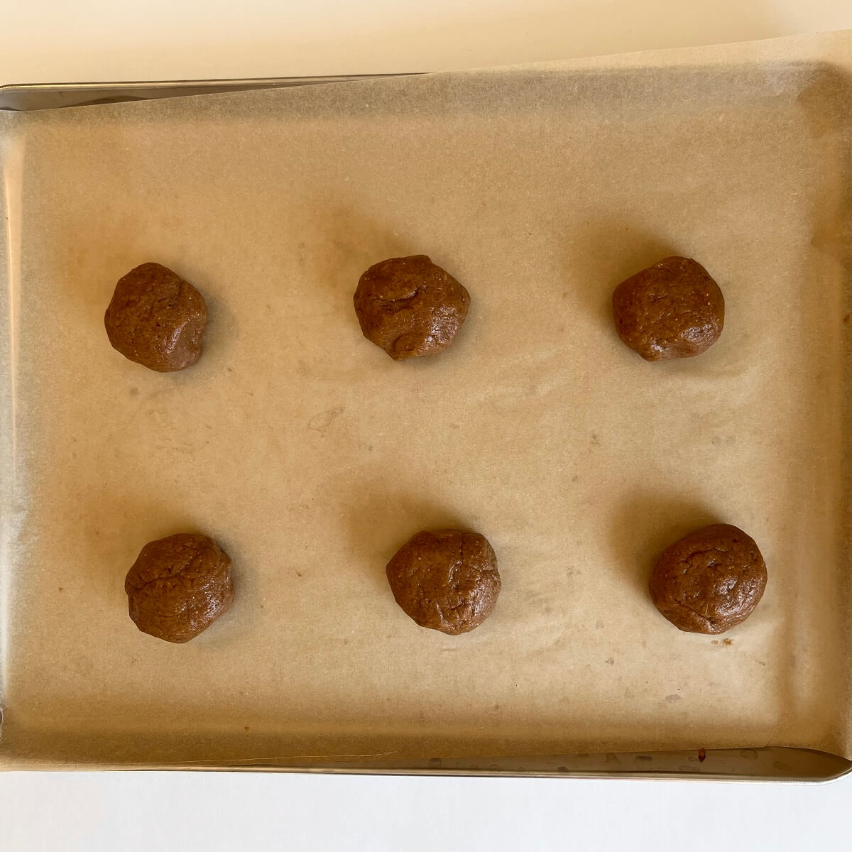 Fig dough balls on a sheet pan lined with parchment paper.
