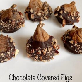 Figs coated with chocolate on a white plate.