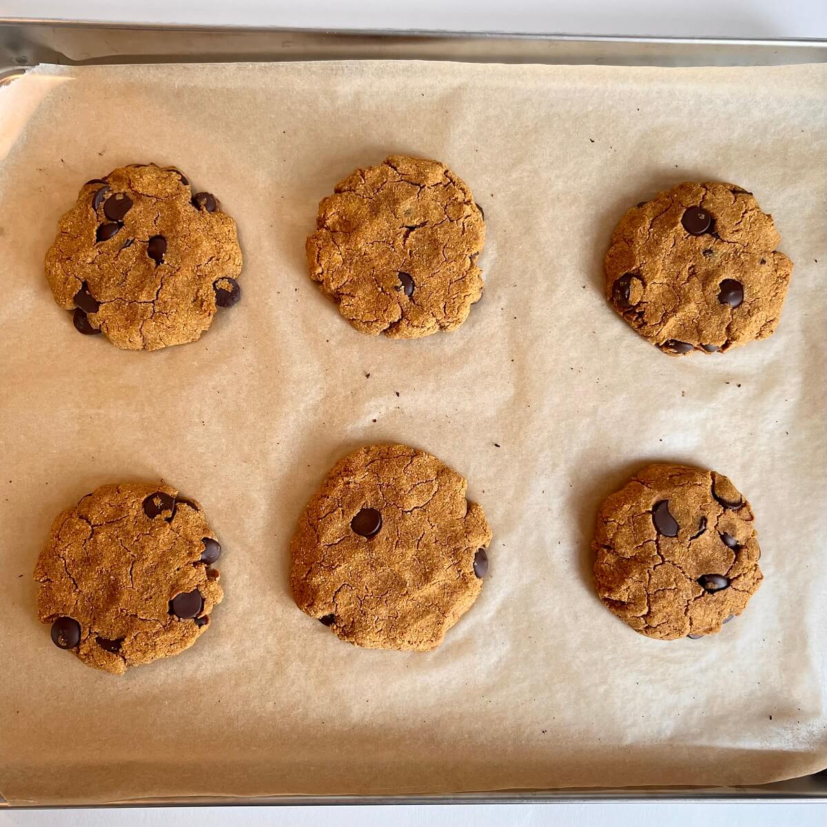 Freshly baked pumpkin cookies on a sheet pan lined with parchment paper.