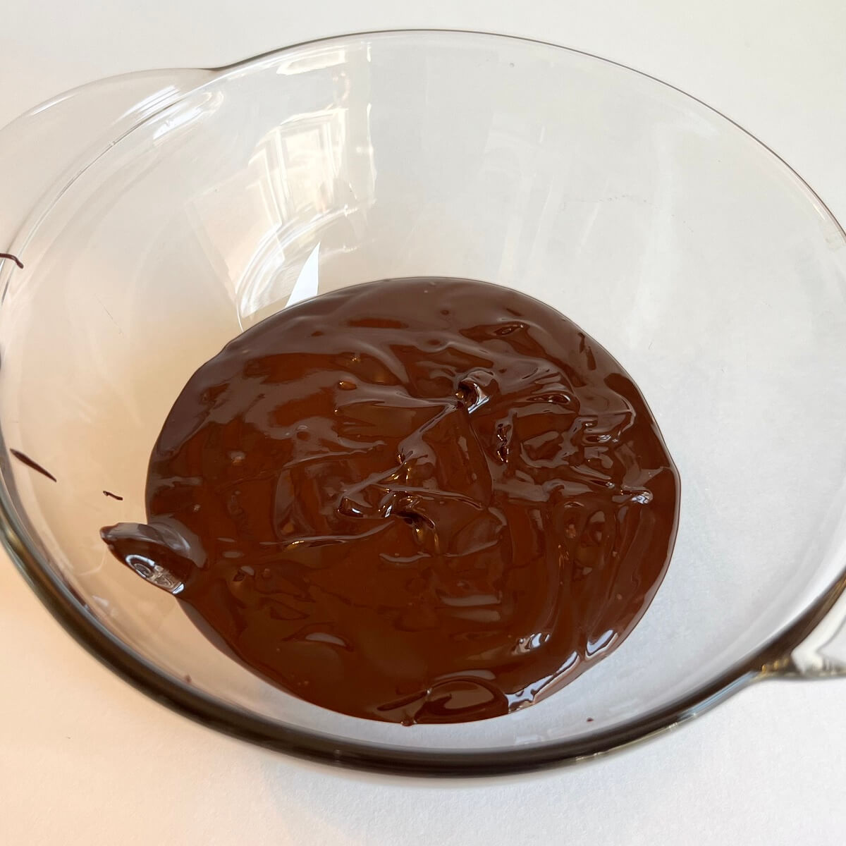 Warm melted dark chocolate in a glass bowl.