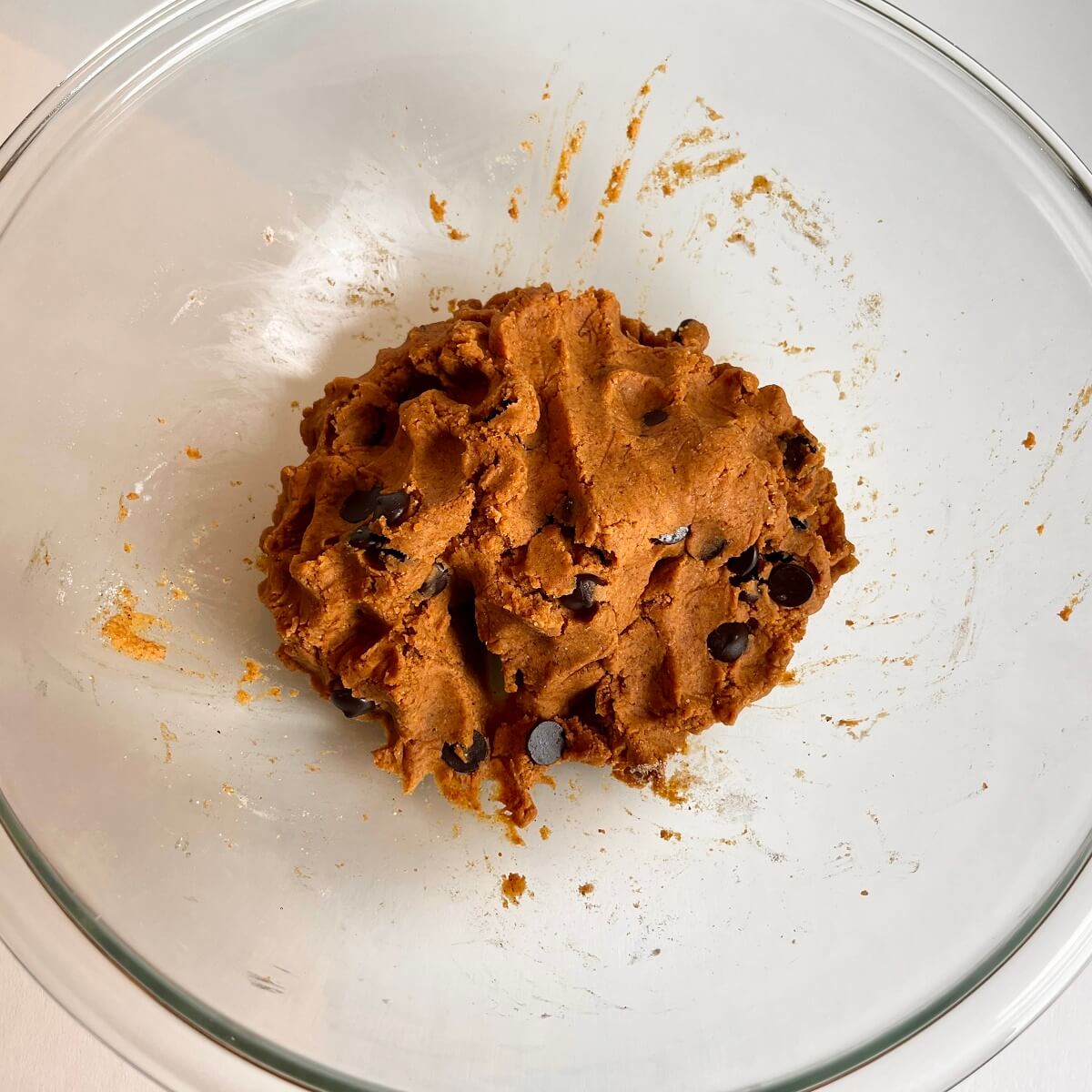 Chocolate chip pumpkin cookie dough in a glass mixing bowl.