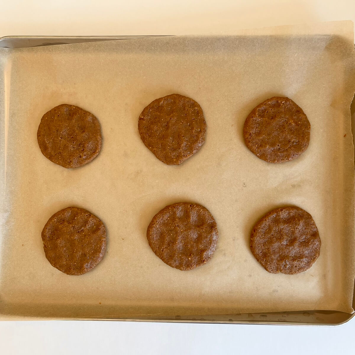 Raw cookies made with figs on a sheet pan lined with parchment paper.