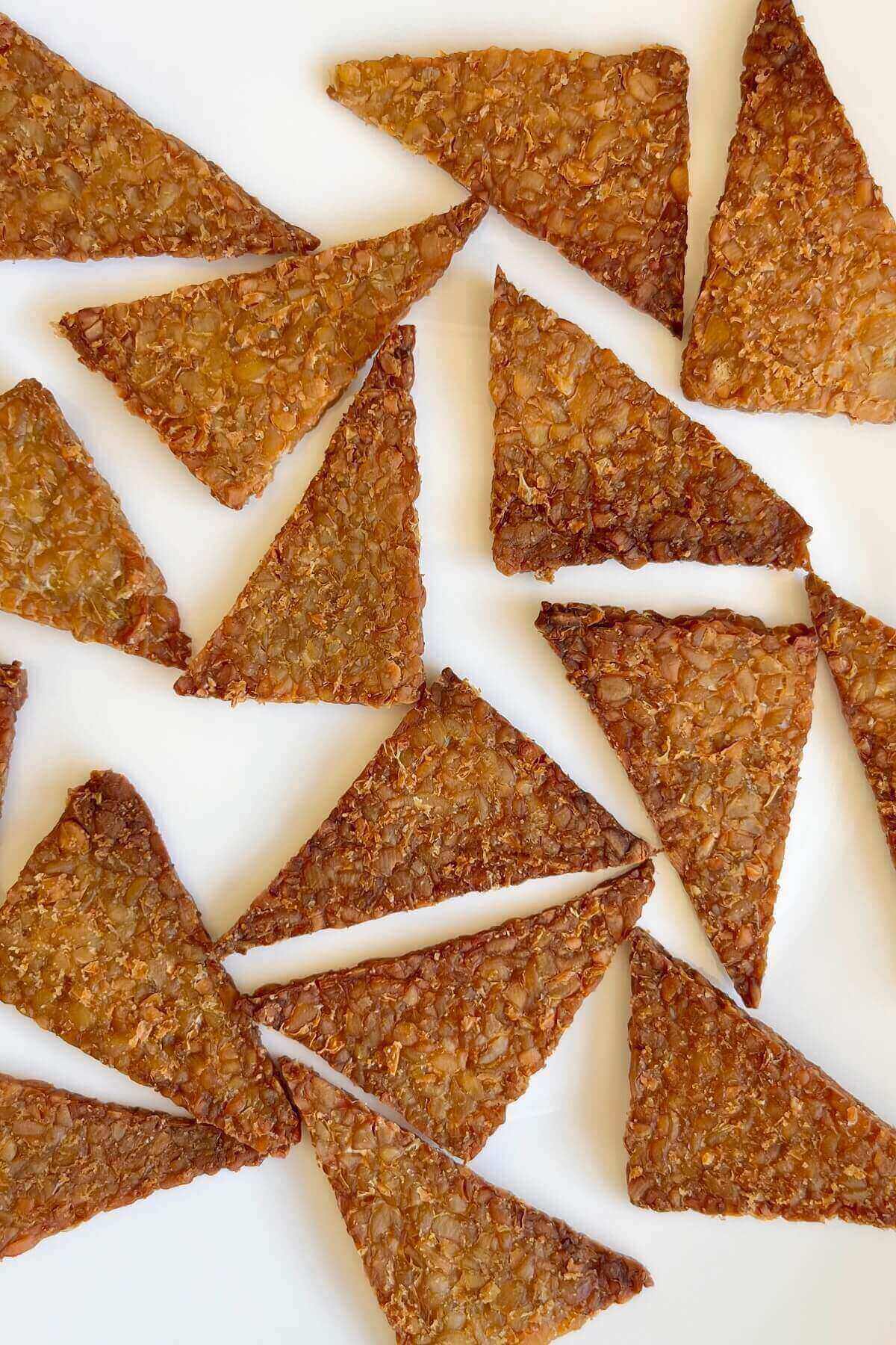 Crispy baked tempeh pieces on a white plate.