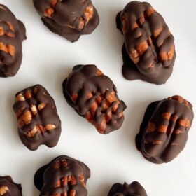 Chocolate covered pecans on a white platter.