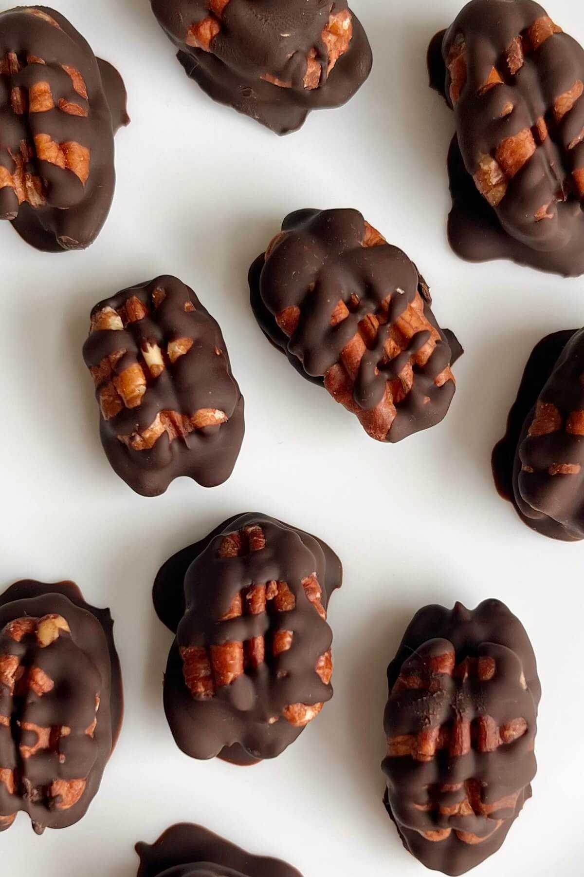 Chocolate dipped pecans on a white plate.