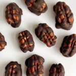 Chocolate covered pecans on a white plate.