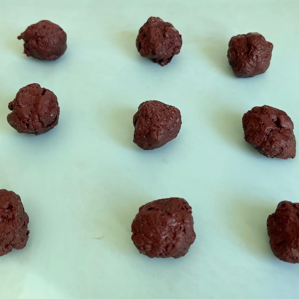 Lavender chocolate balls on a turquoise baking mat.