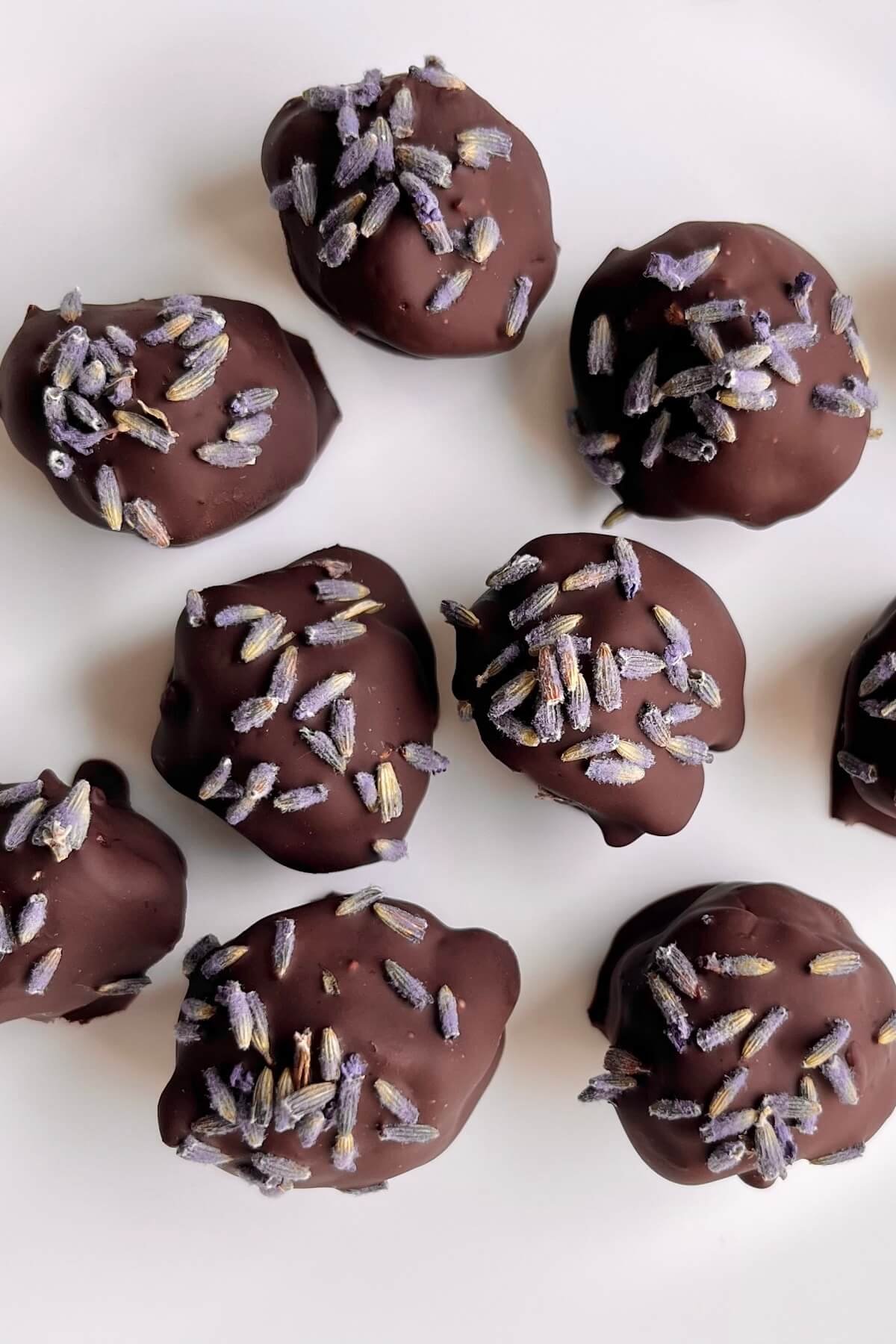 Lavender chocolate truffles on a white platter.