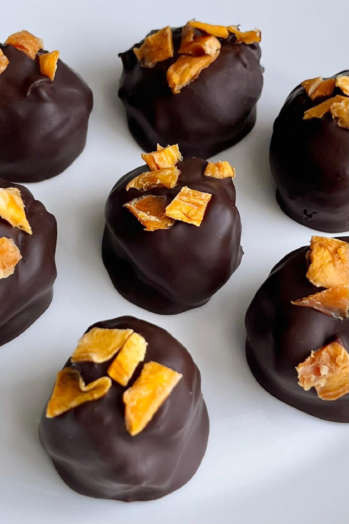 Mango chocolate truffles on a white platter.