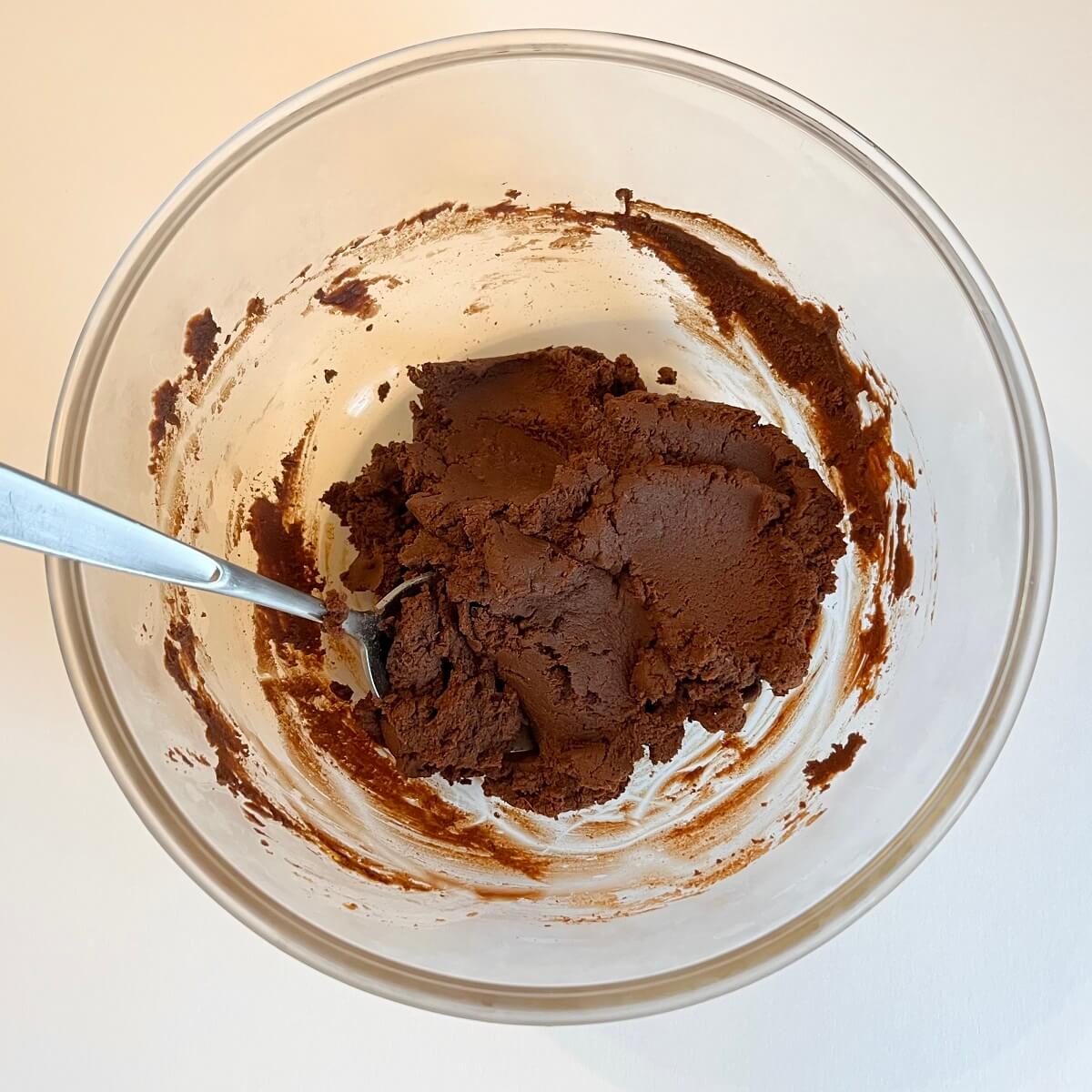 A mixture of pumpkin puree, melted chocolate, and pumpkin pie spice in a glass bowl.