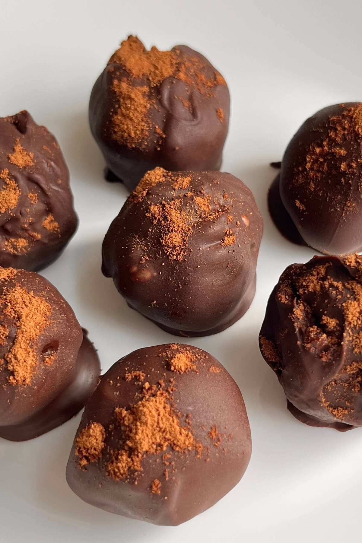 Pumpkin chocolate truffles on a white plate.