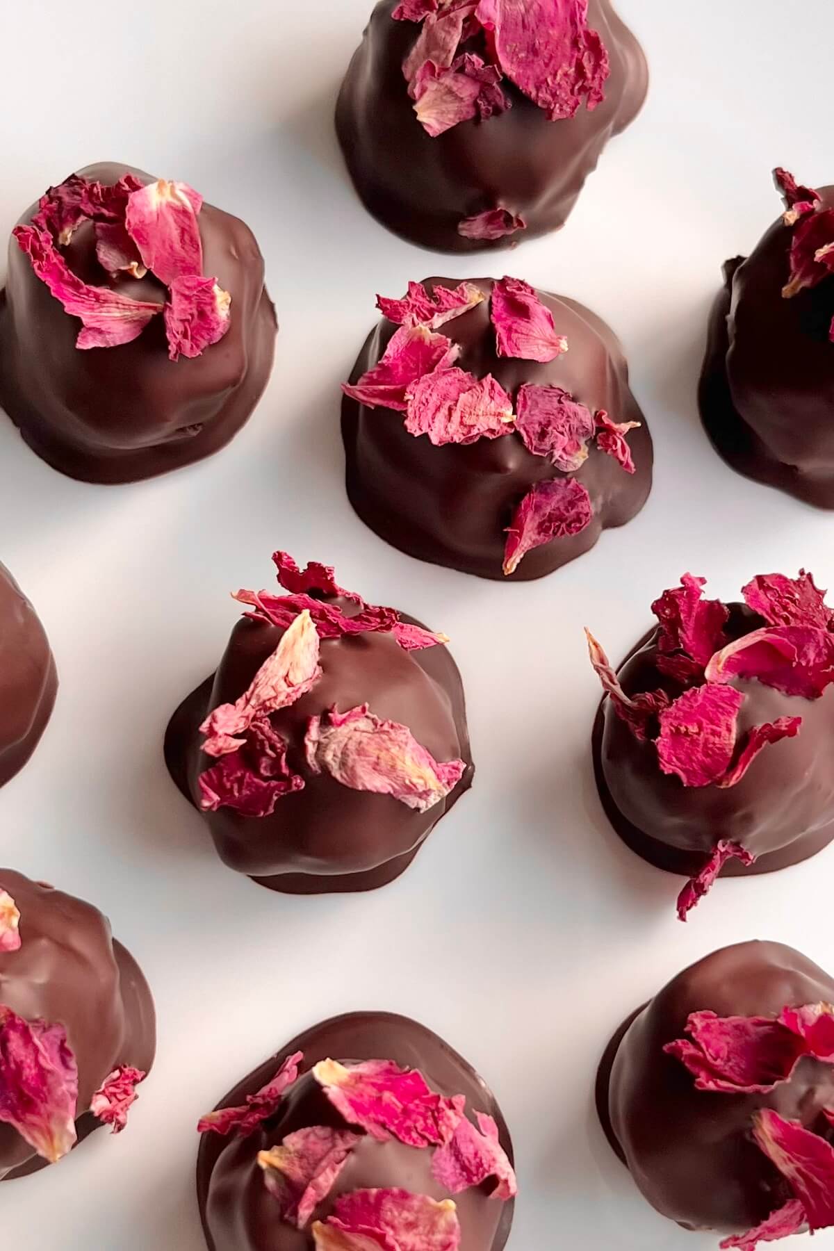 Rose chocolate truffles on a white platter.