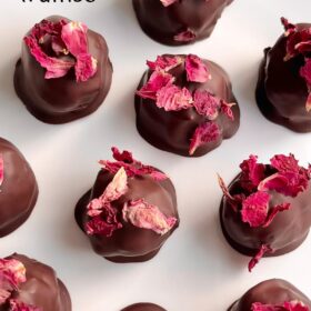 Rose petal topped chocolates on a white plate.