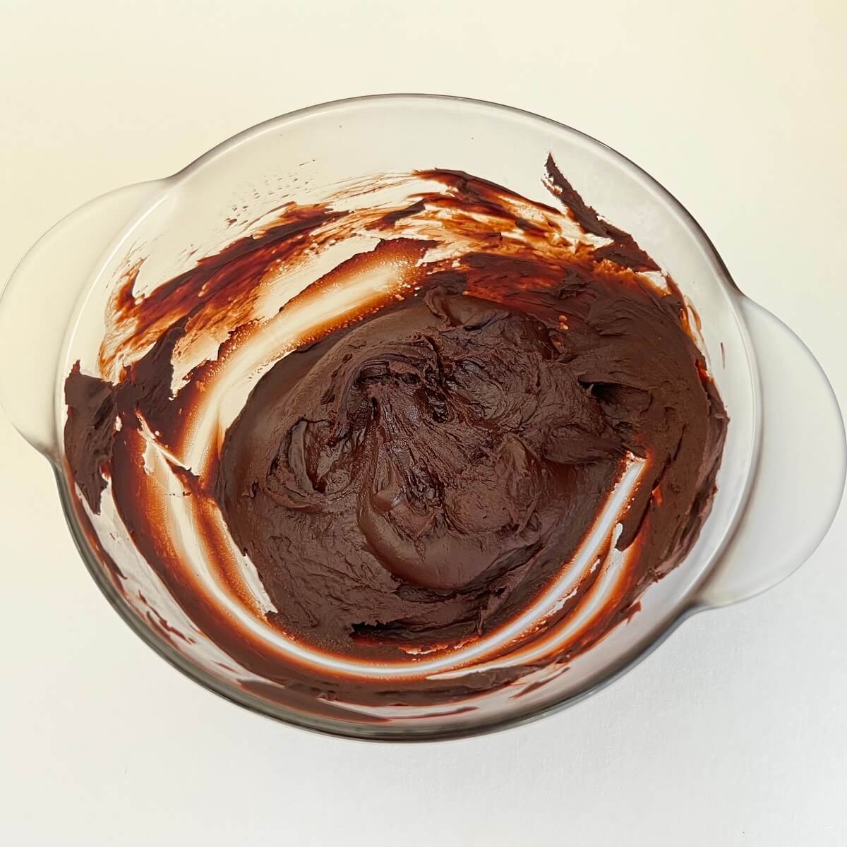 Rose water and melted chocolate mixed together in a glass bowl.