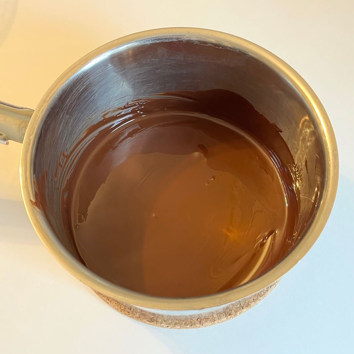 Melted warm dark chocolate in a steel pot.