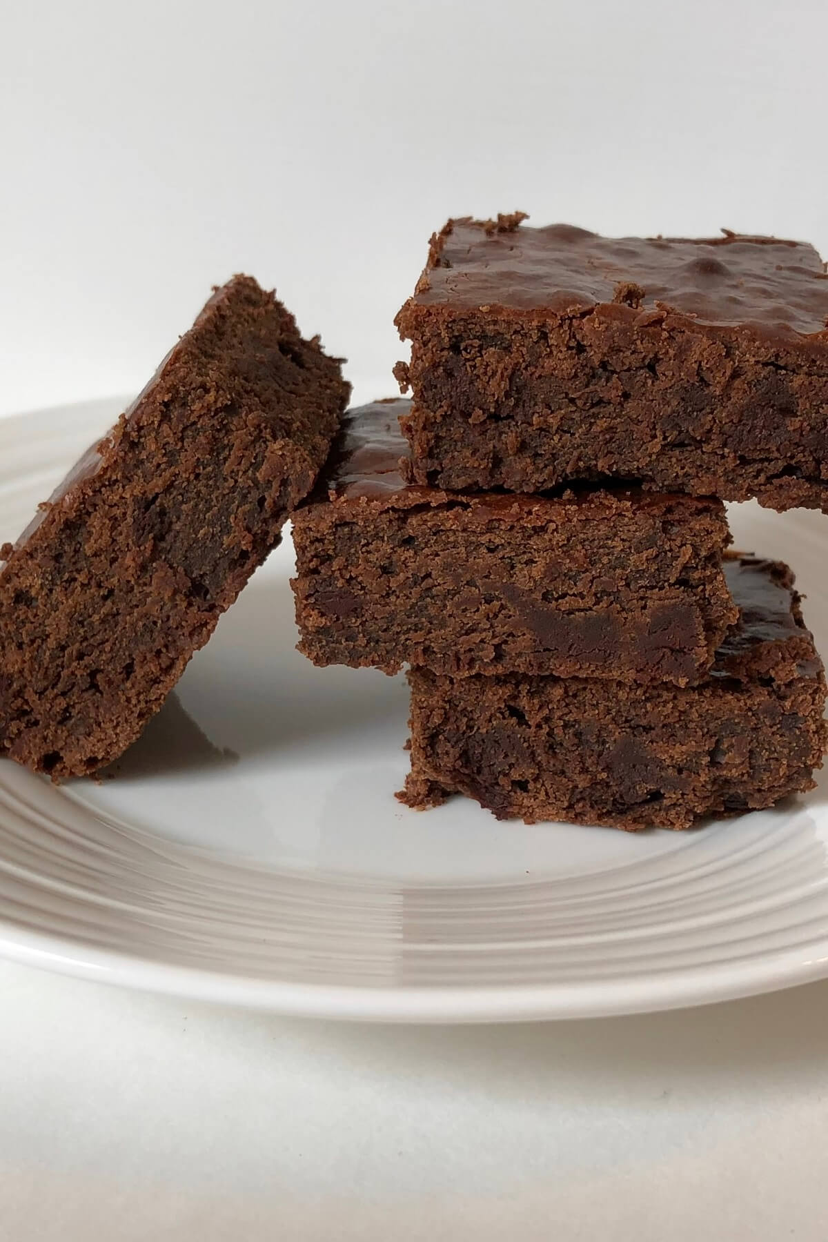 Four thick brownies stacked on a plate.