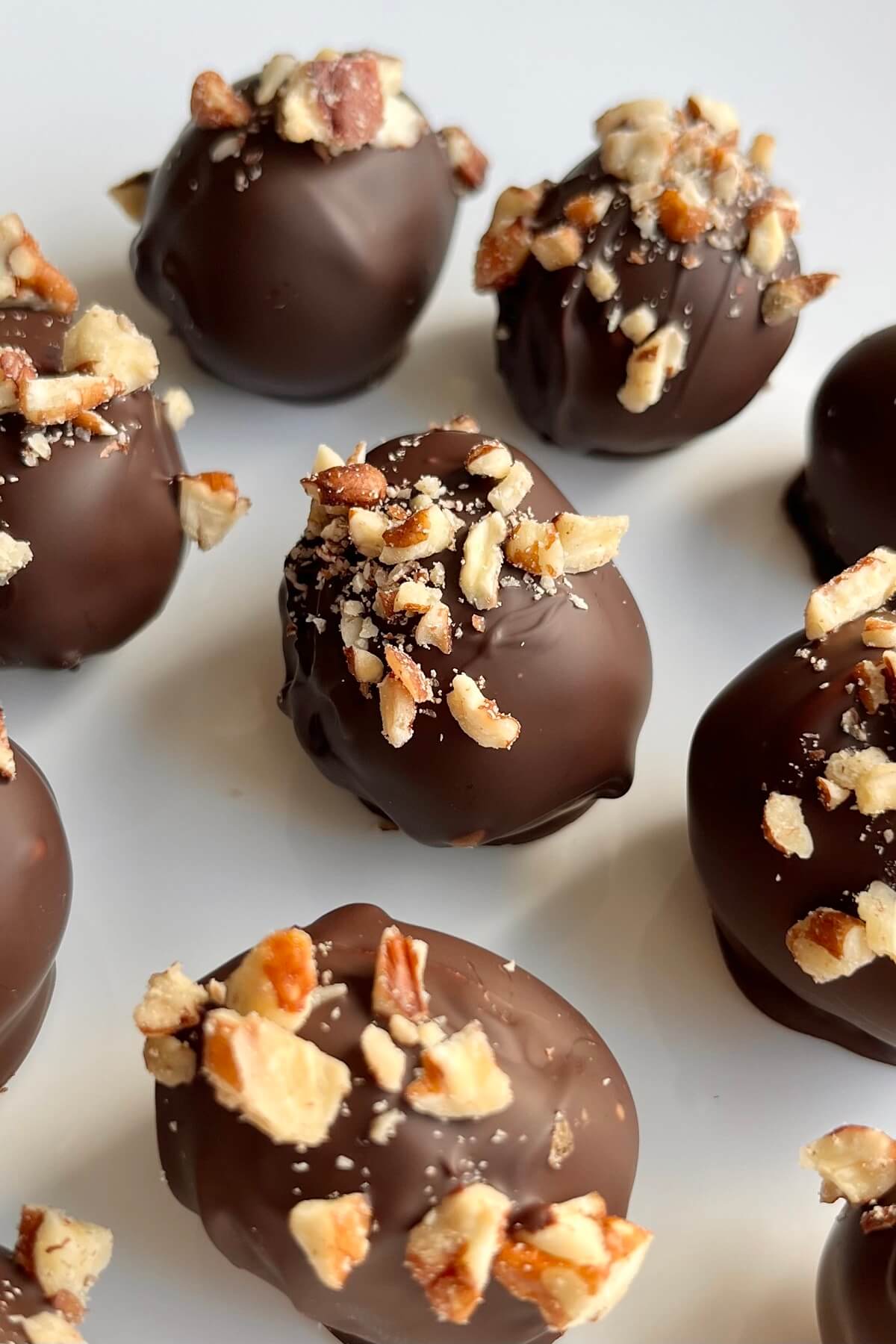 Chocolate dipped grapes on a white plate.