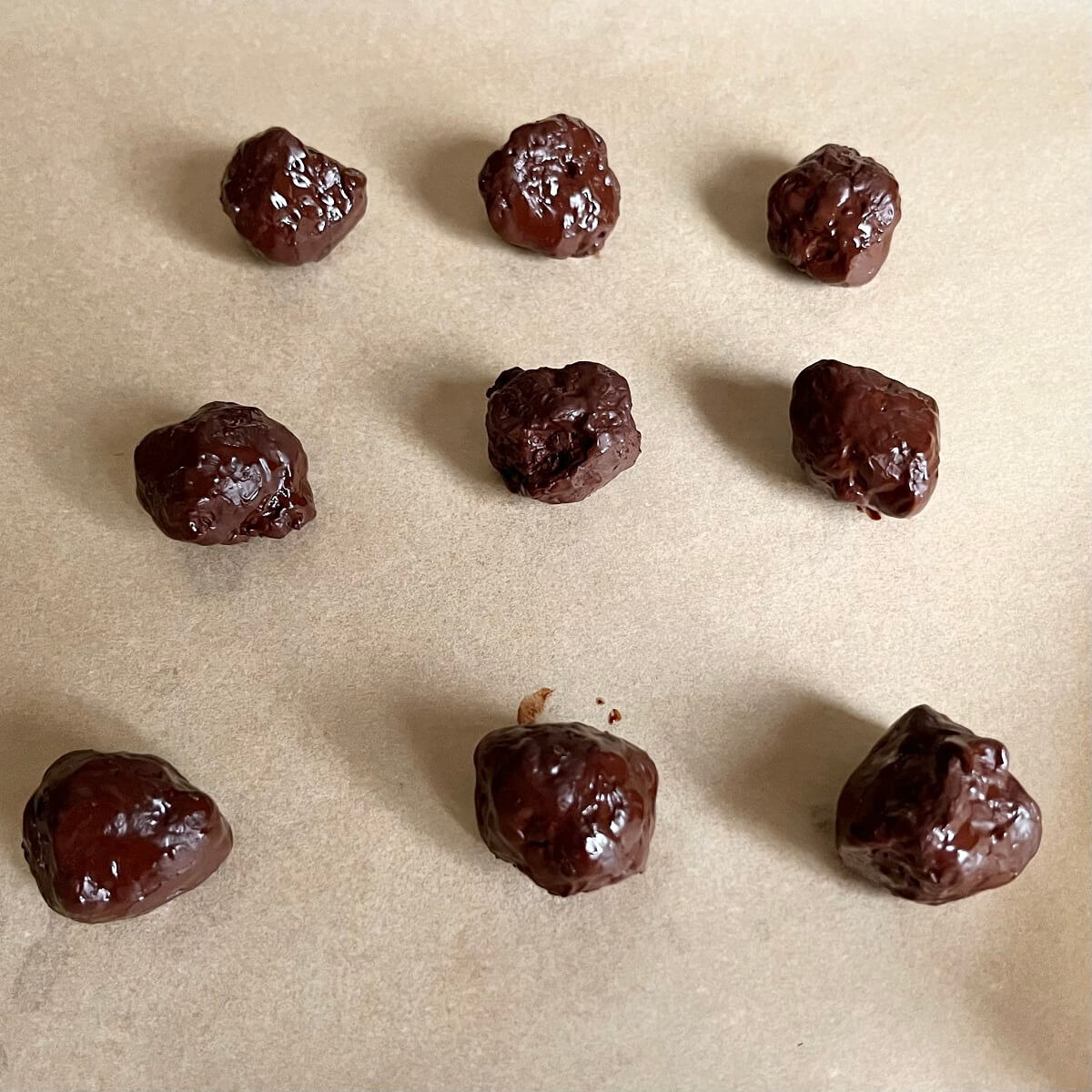 Chocolate olive oil balls on a piece of parchment paper.