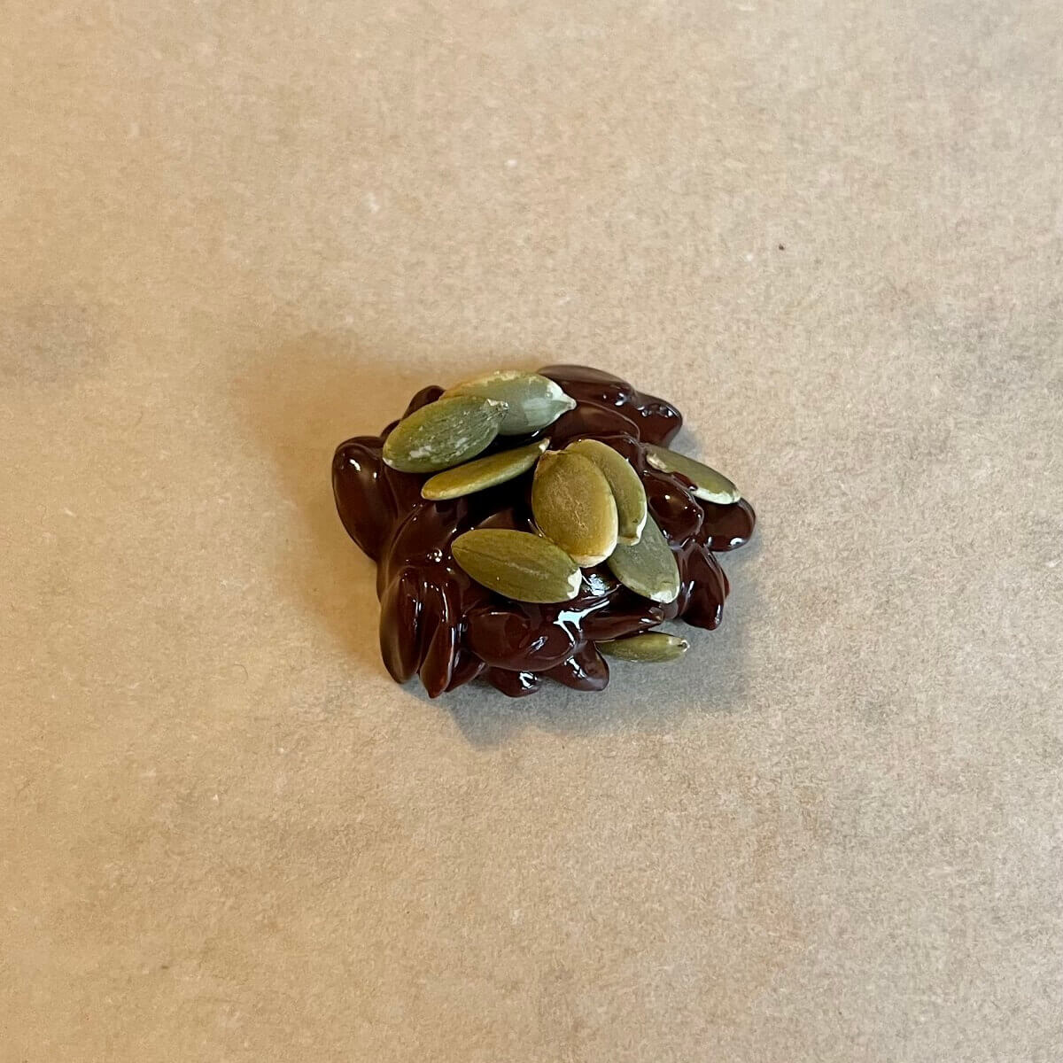 Chocolate pumpkin seeds on parchment paper.