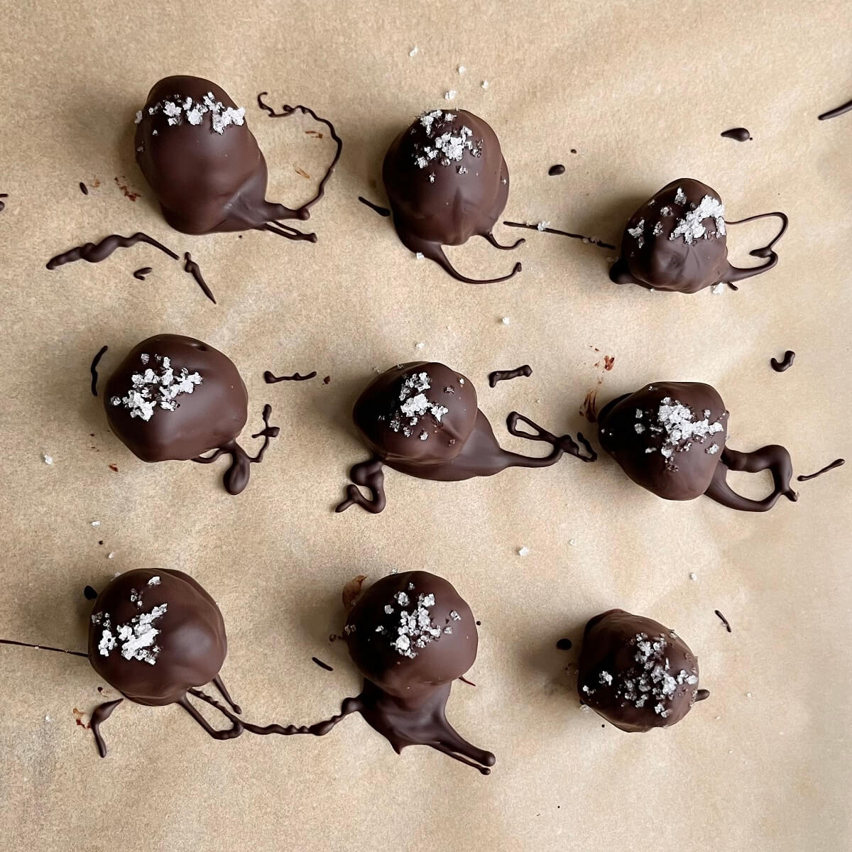 Chocolate truffles sprinkled with sea salt on parchment paper.