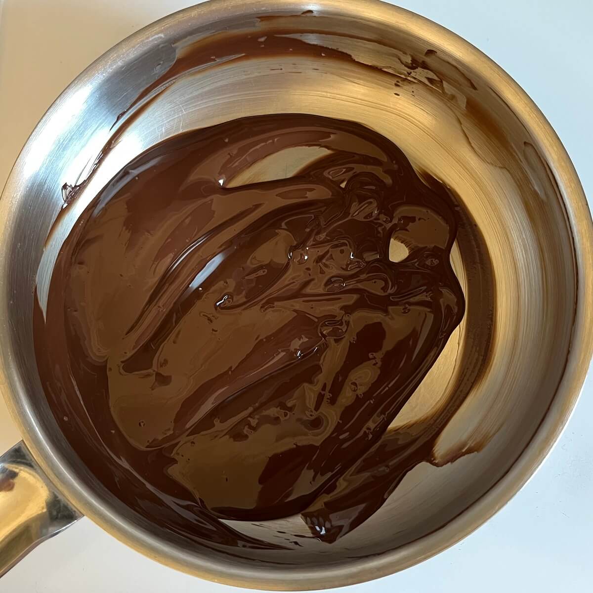 Melted dark chocolate in a steel pan.
