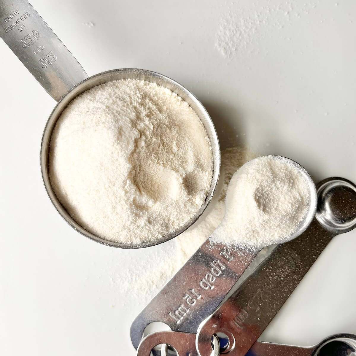 A measuring cup and spoons filed with high fiber coconut flour.