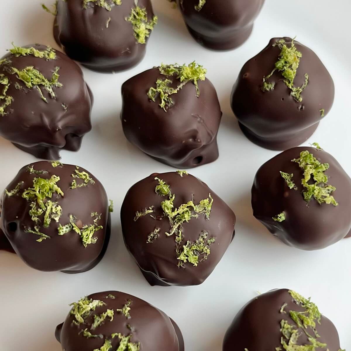 Chocolates sprinkled with lime zest on a white plate.