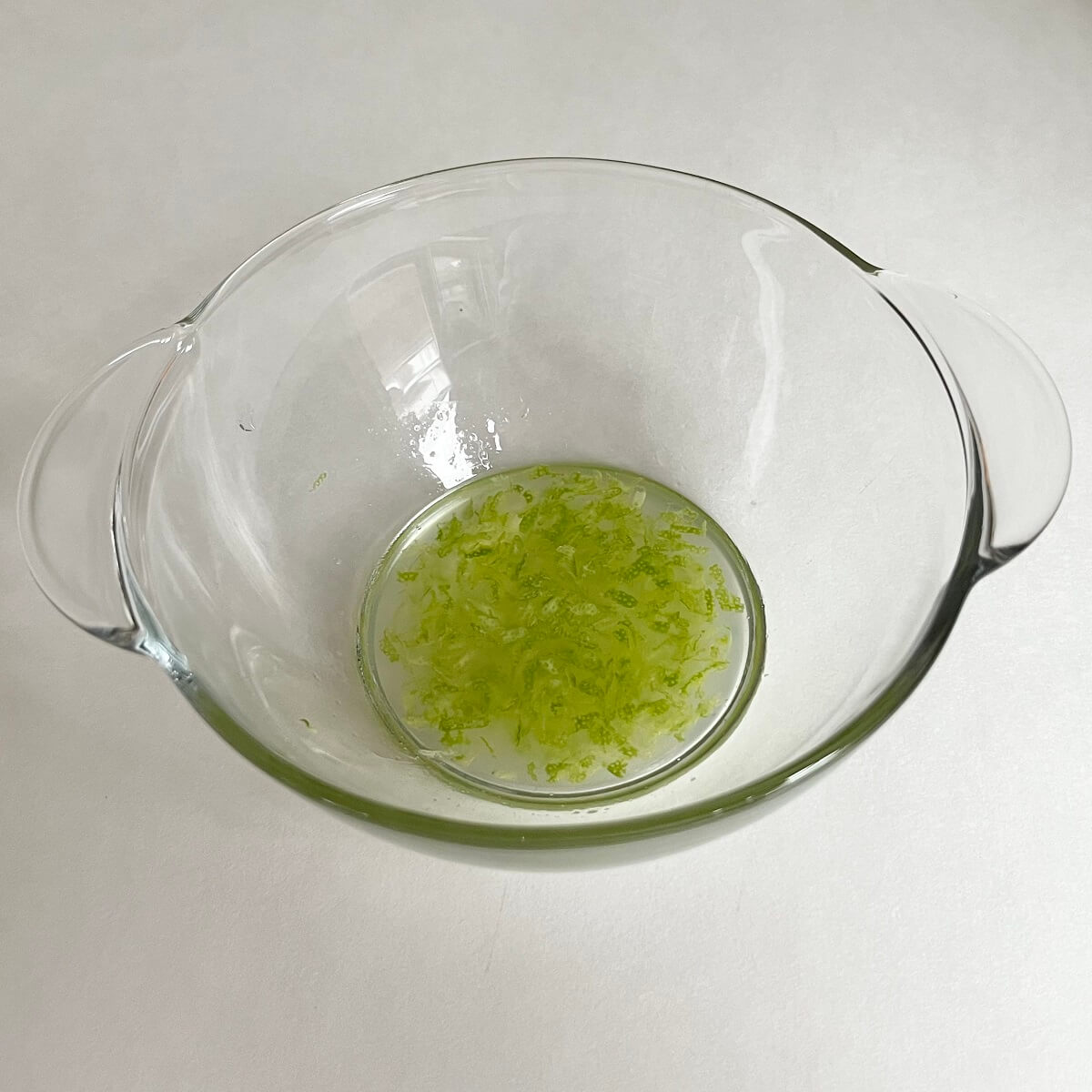 Lime zest and juice in a glass bowl.