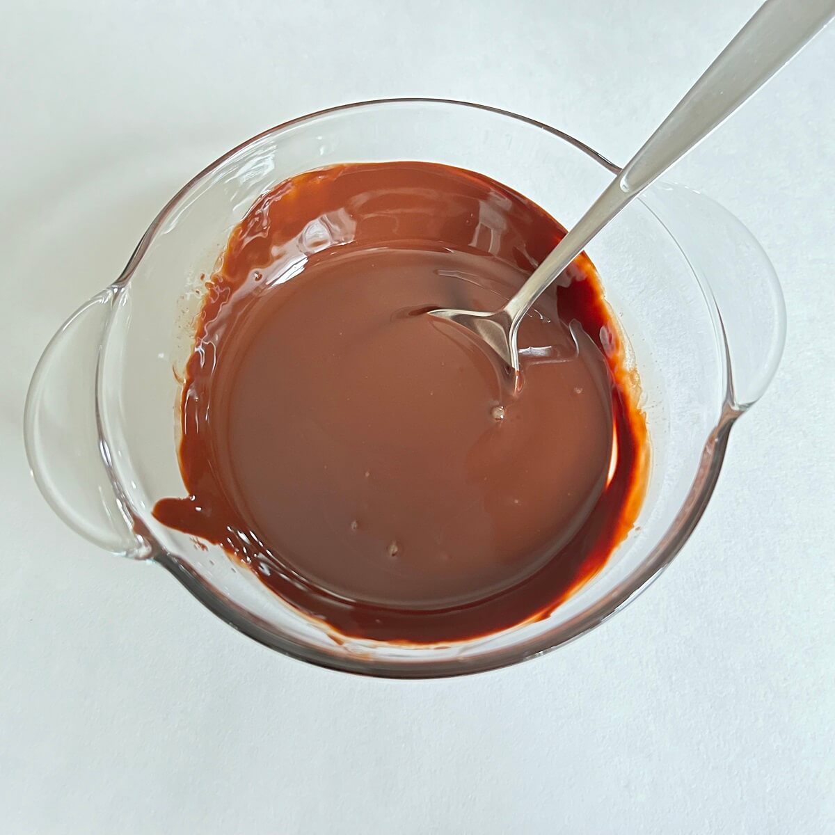 A liquid mixture of melted chocolate and extra virgin olive oil in a glass bowl.