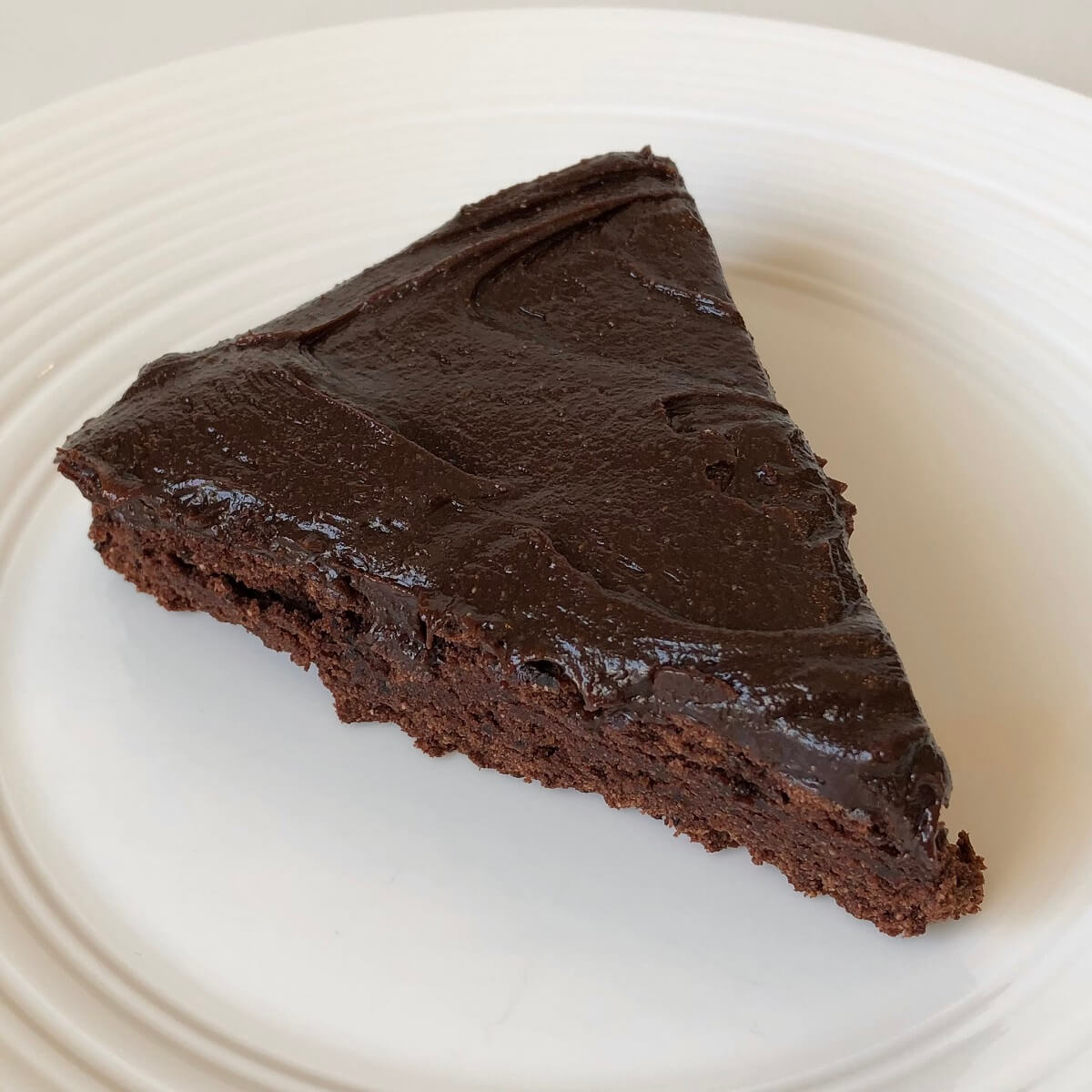 A slice of naturally sweetened chocolate cake on a white plate.