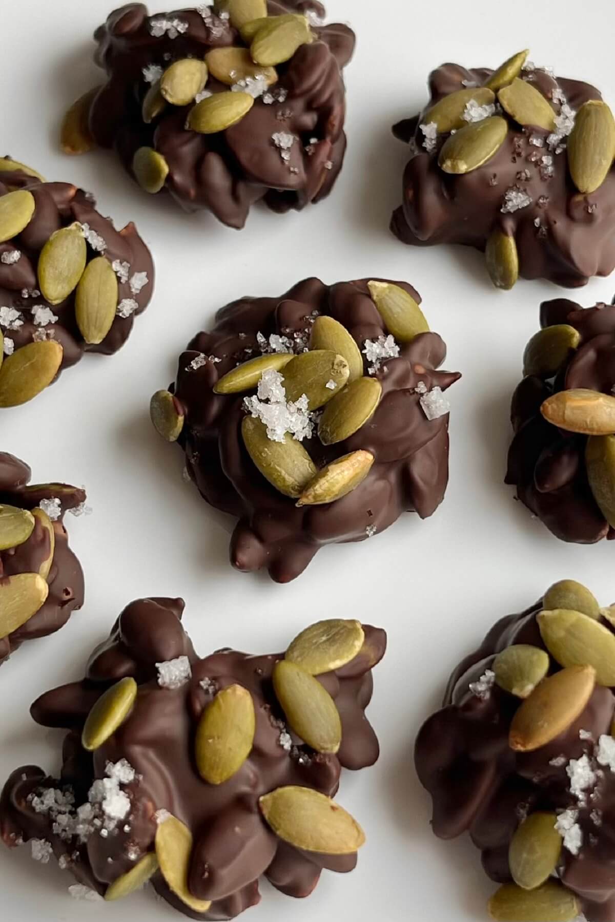 Pumpkin seed clusters coated in dark chocolate with a sprinkle of sea salt on top.