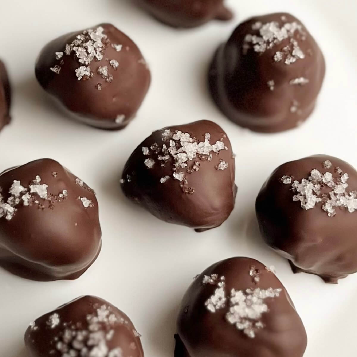 Olive oil chocolates sprinkled with sea salt on a white plate.
