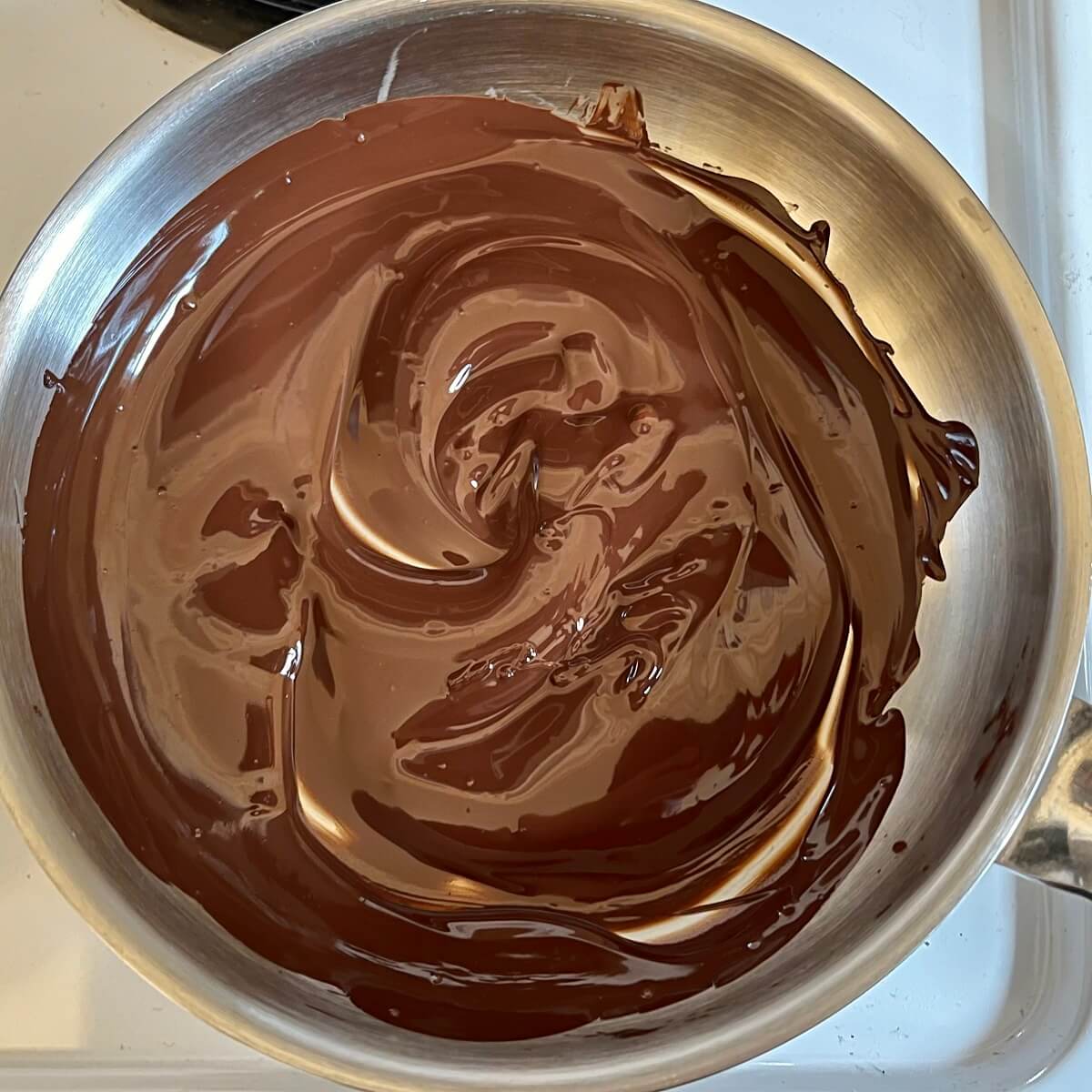 Melted dark chocolate in a metal pan.